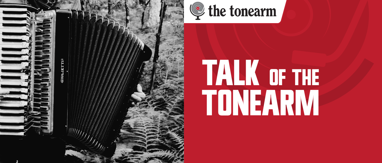 A black-and-white Giulietti accordion stands among ferns in woodland, beside a red panel reading "TALK OF THE TONEARM" with the tonearm logo above it.