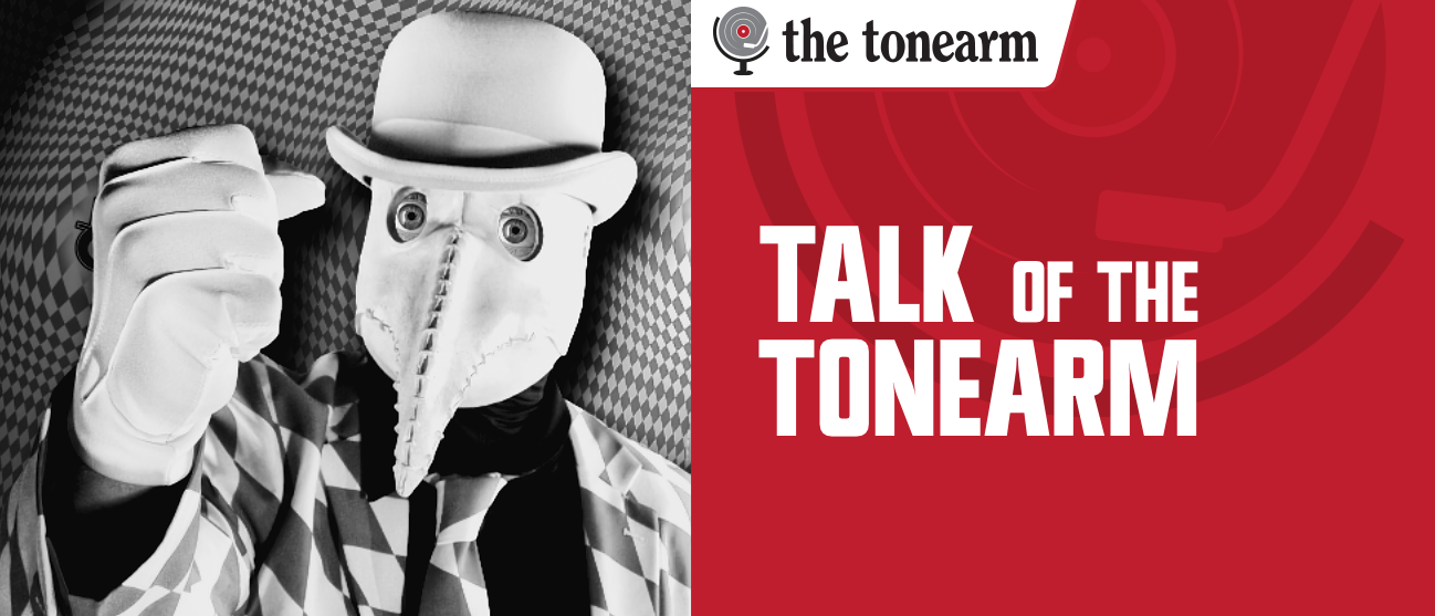Black-and-white photo of a figure in a bowler hat, white gloves, and a beaked mask with bulging eyes, beside a red panel reading "Talk of the Tonearm" and The Tonearm logo.