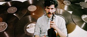 Frank Fairfield holds a fiddle to his chin, mustachioed and wearing a striped shirt, surrounded by a collage of vintage 78 rpm records.