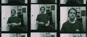 Contact sheet of black-and-white film frames showing Arthur Russell seated in a book-lined apartment, hands folded in his lap, in three slightly varied poses.