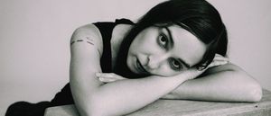 Concepción Huerta rests her head sideways on her folded arms on a wooden surface, looking directly at the camera, in black and white.