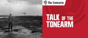 The Talk Of The Tonearm masthead: a red title panel beside a grainy black-and-white photo of a lone figure standing on a rocky tidal flat, a shipyard crane on the horizon.
