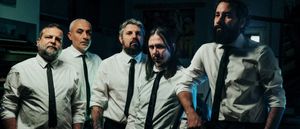 The five members of Calibro 35, in white shirts and black ties, stand shoulder to shoulder in a darkened studio, keyboards at the edge of the frame.