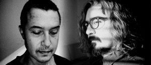 Black-and-white double portrait: Eugene Thacker, head lowered and eyes cast down, beside Siavash Amini in profile with long hair and round glasses, both set against deep shadow.