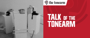 Grainy black-and-white photo of rotary telephones on white plinths around a clear chair, beside a red panel reading “Talk Of The Tonearm” with The Tonearm logo.