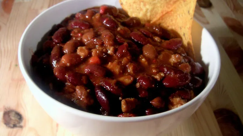Bowl of homemade chili with a spoon on a table.