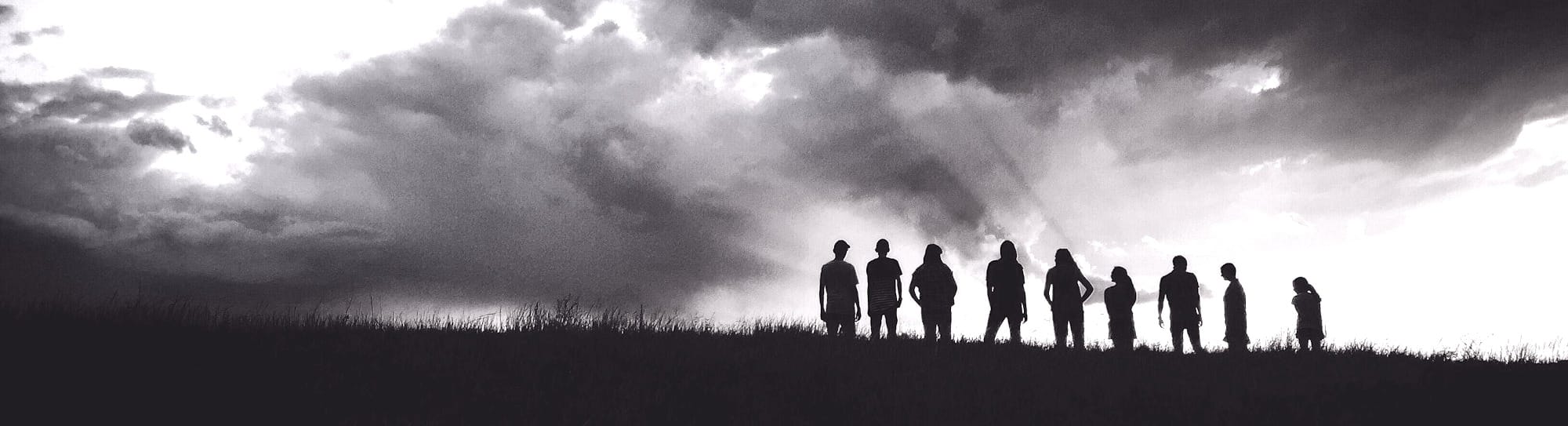 silhouette of nine persons standing on the hill