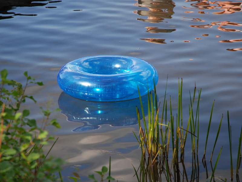 A clear blue inner tube floating in a murky lake