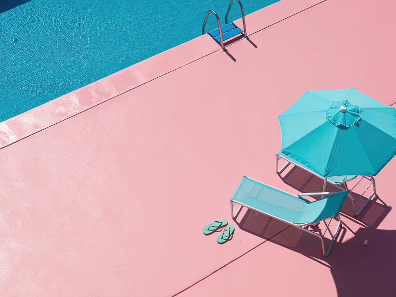 Solo travel lounge chair and flip flops on a pink pool deck. 