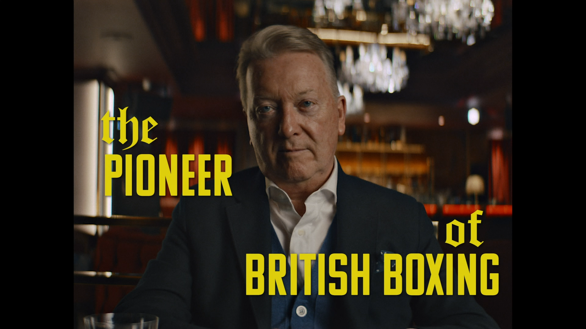 Frank Warren doing a very Frank Warren face. The text on the screen says "the PIONEER of BRITISH BOXING"