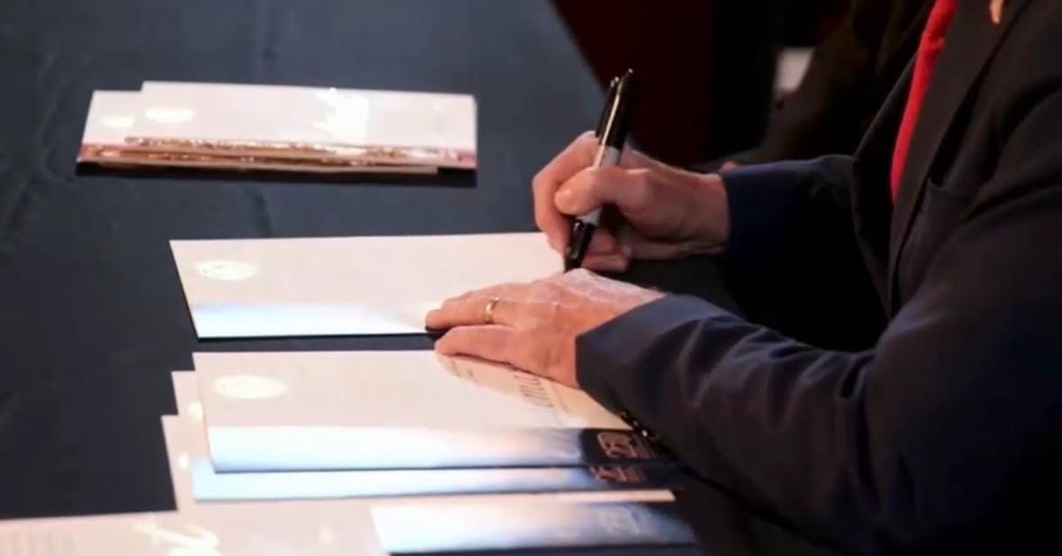 A ceremonial copy of the COINSOLATION trademark registration on the signing table, Washington D.C., 23 July 2026.