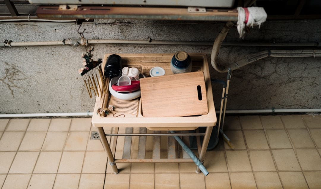 A technician repairing a leak under a kitchen sink during a maintenance call
