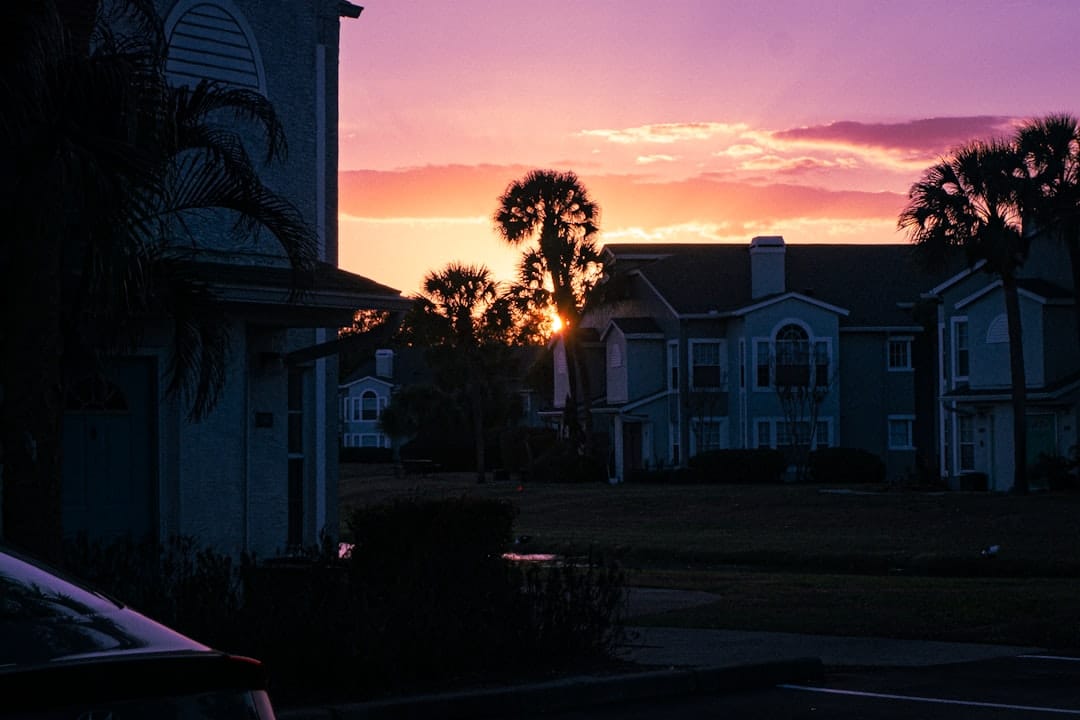 Florida townhomes and palm trees silhouetted against a sunset sky
