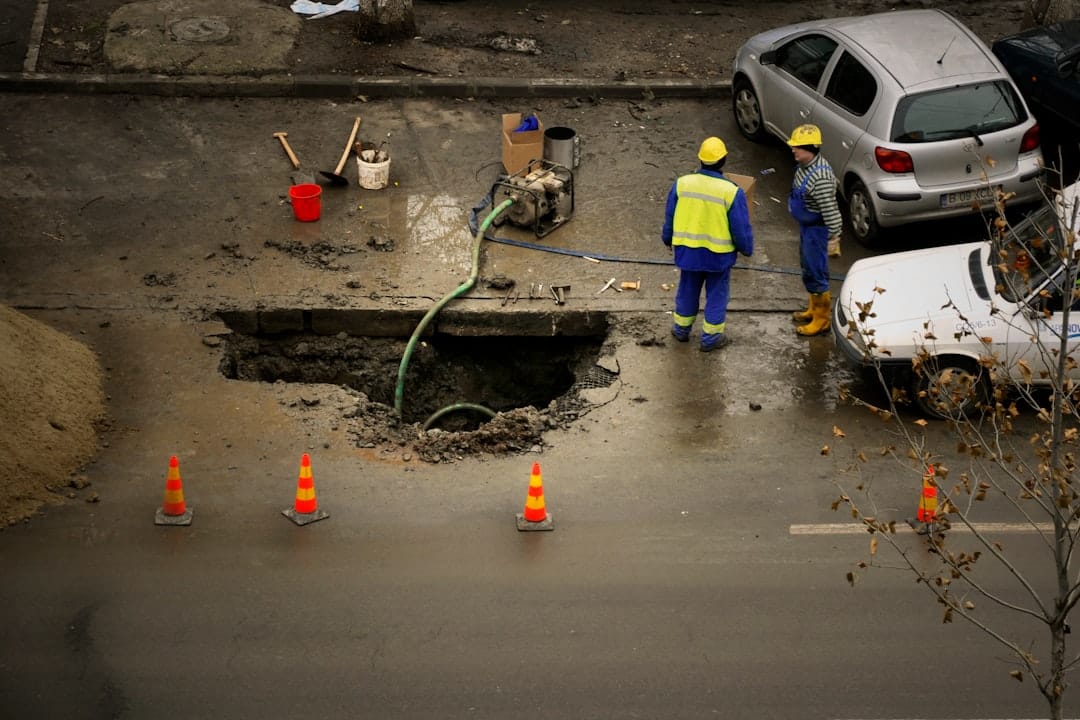 Workers beside an open utility excavation in a street