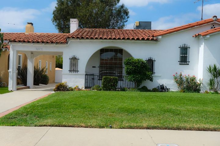 White stucco Florida rental home with a barrel-tile roof and front lawn