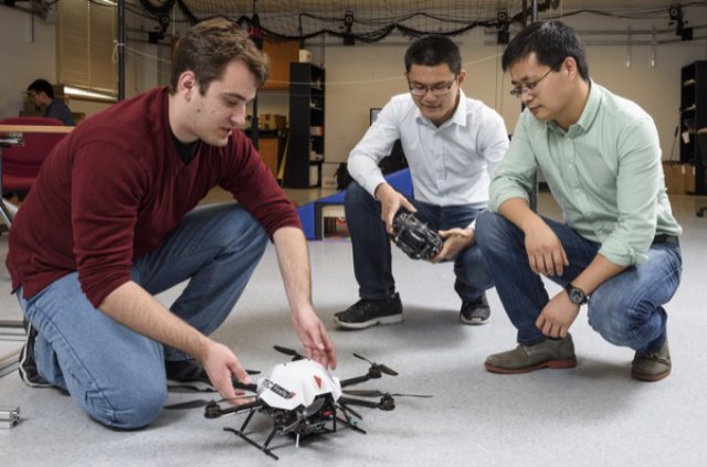 Guoquan Huang (right) works on a micro aerial vehicle with graduate students Kevin Eckenhoff (left) and Yulin Yang.