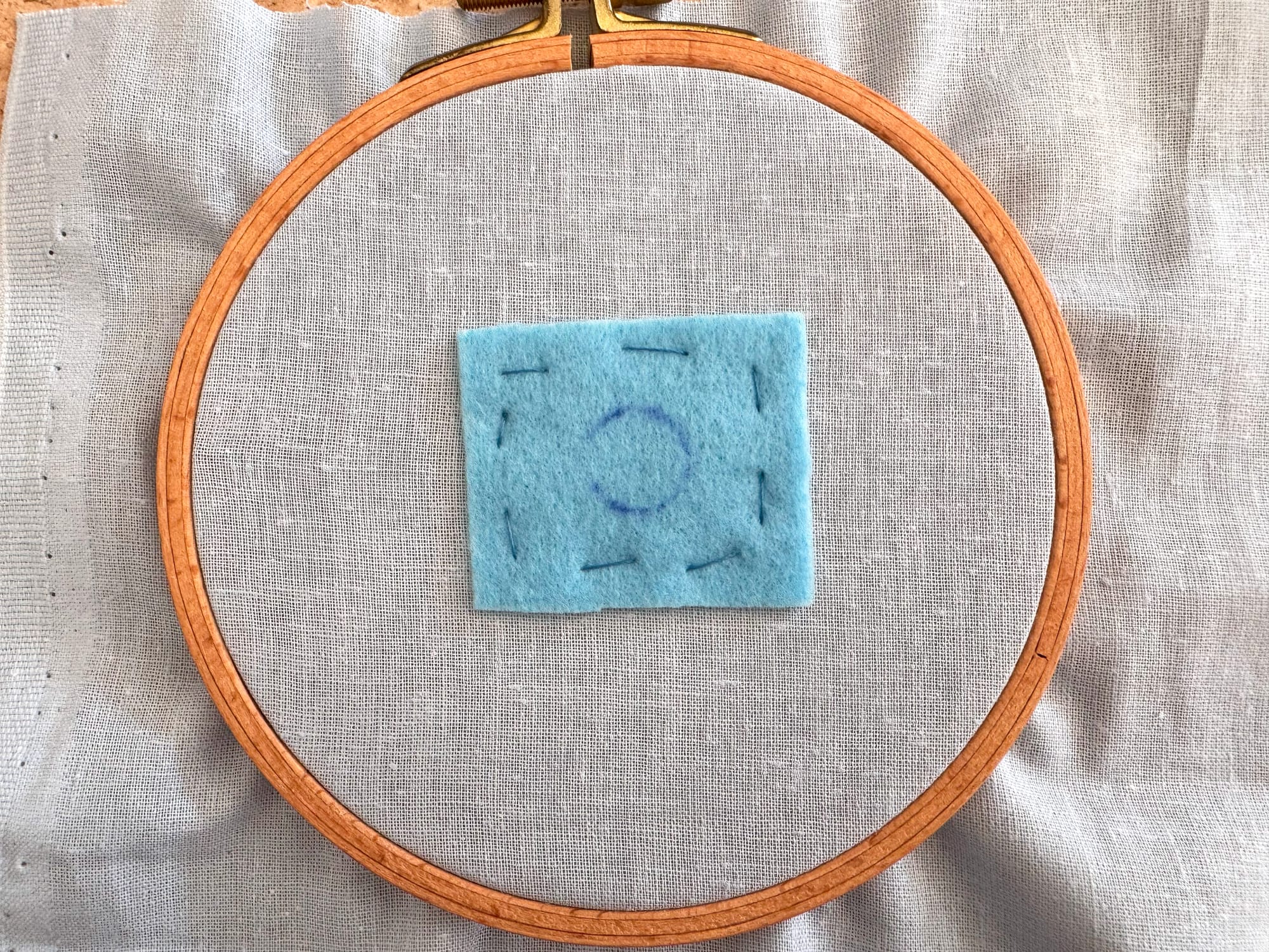 A piece of felt with a marked circle stitched to the fabric base and inserted into embroidery hoops