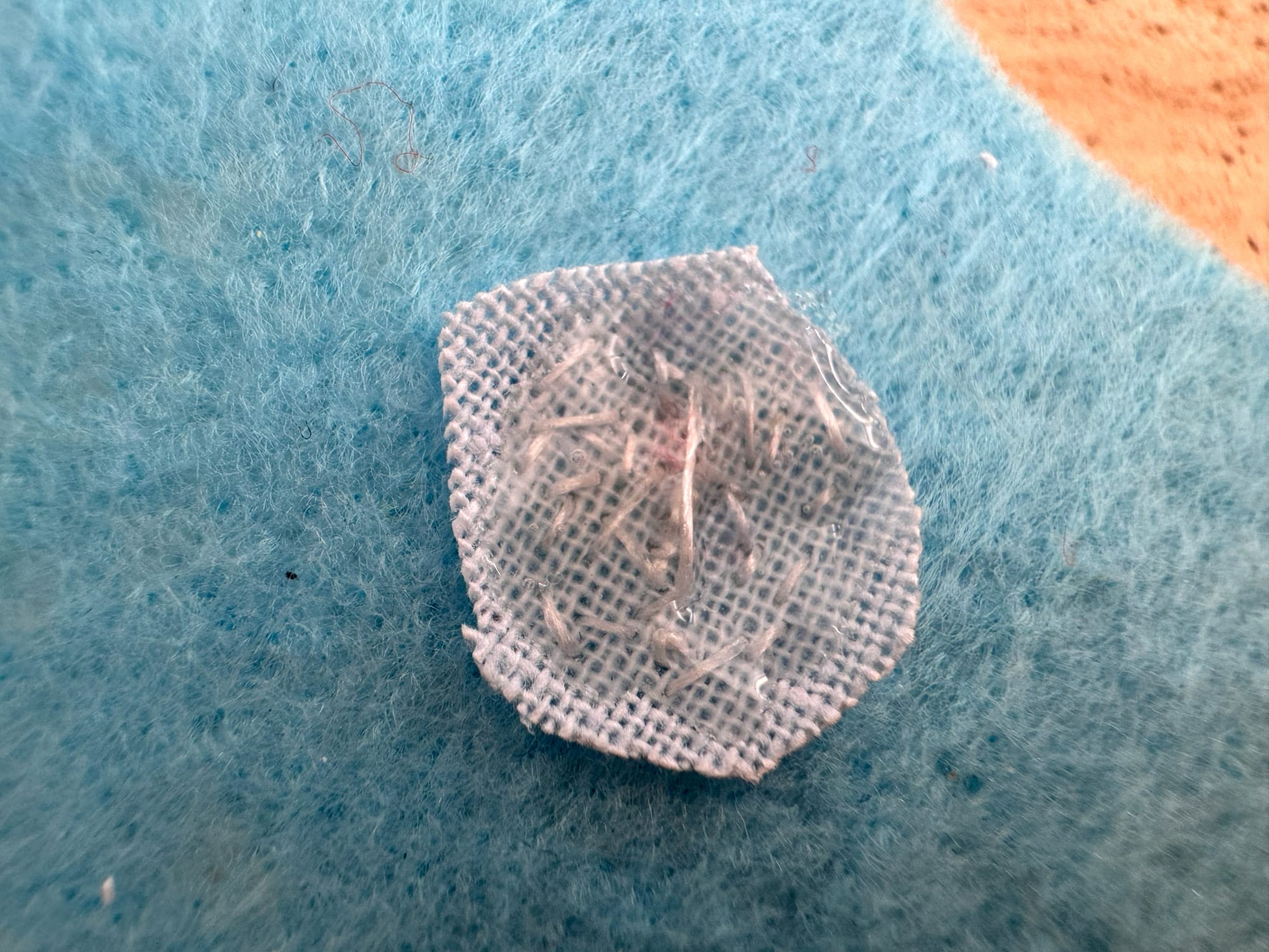 The wrong side of the stitched work with jewelry glue applied