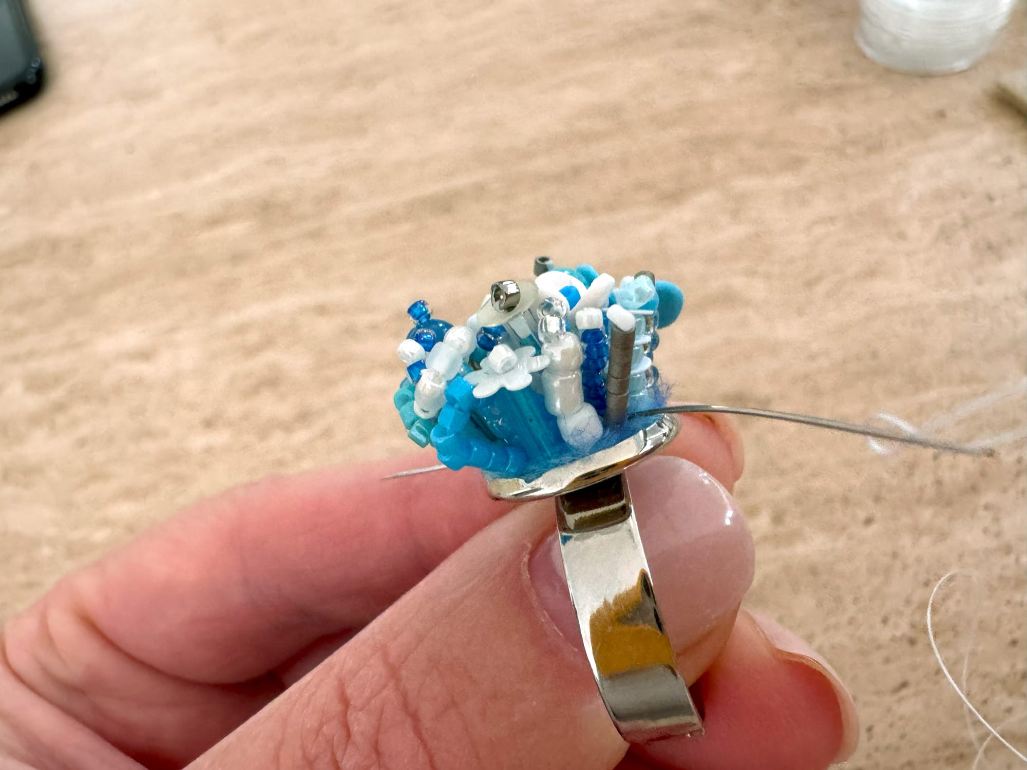 The needle goes into the center of the beadwork and existing at the edge of the ring