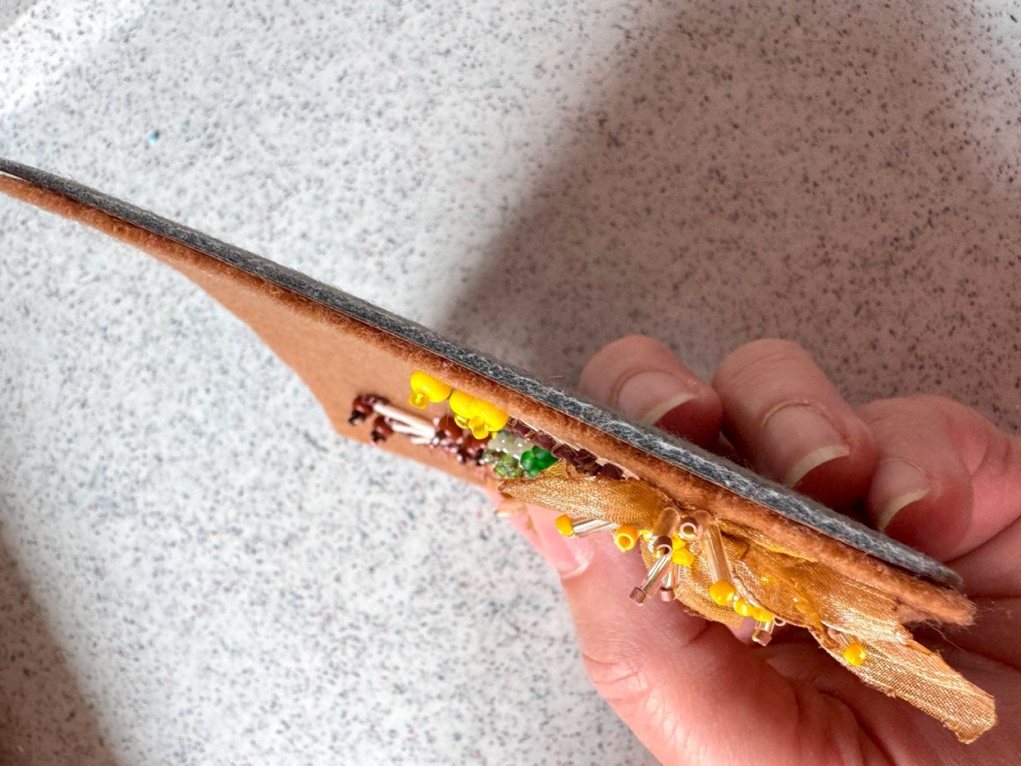 The felt detail is glued to the faux leather detail