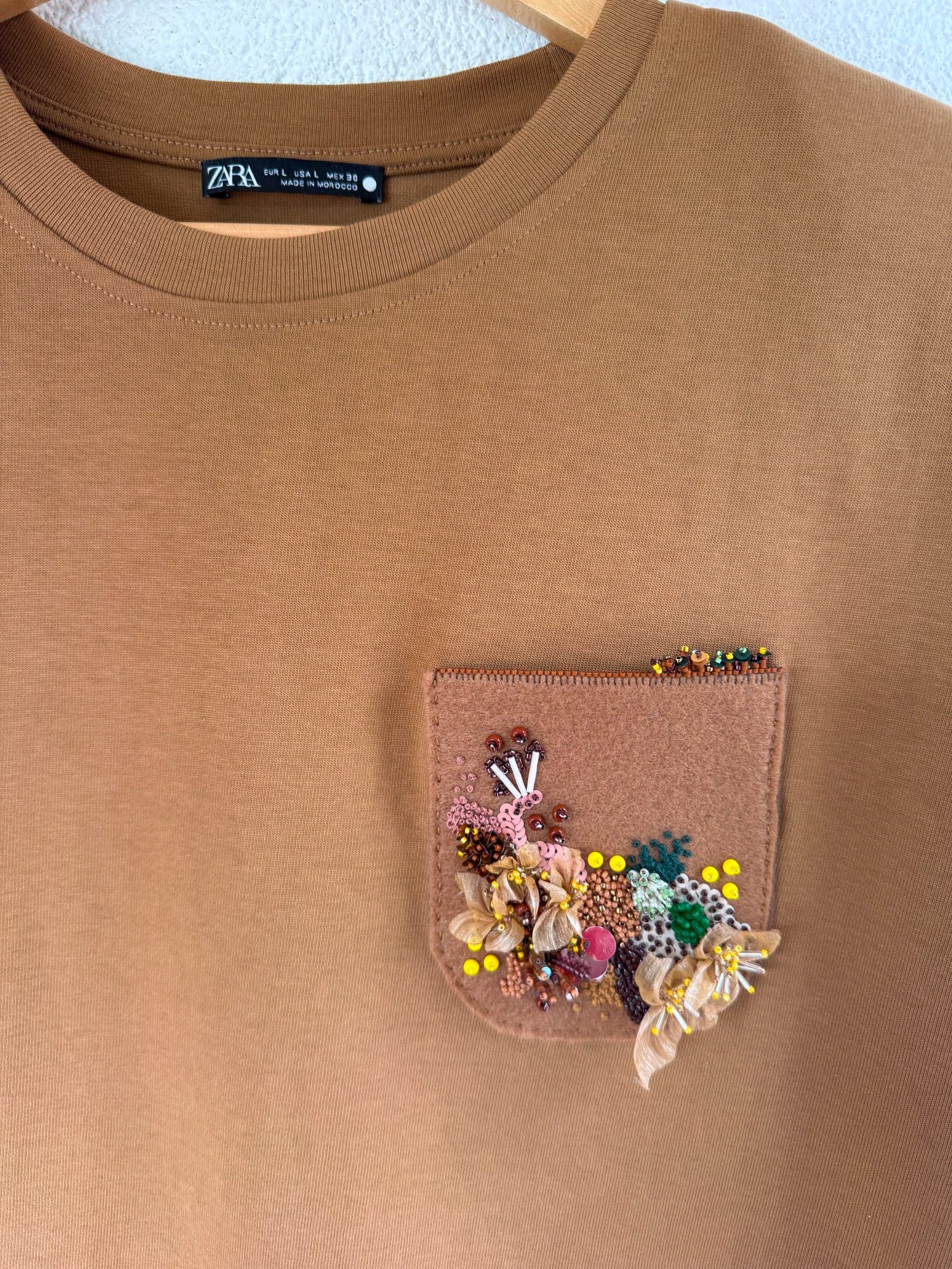 Final view of the pocket decorated with embroidery, fabric flower, beads, and sequins