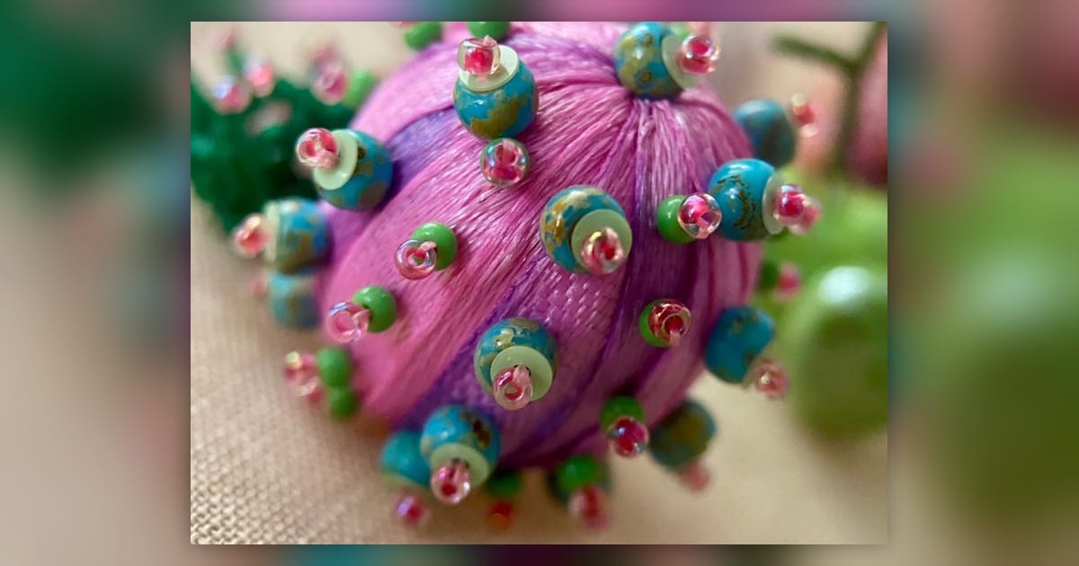 Pink three-dimensional embroidered sea creature decorated with turquoise, green and transparent beads.