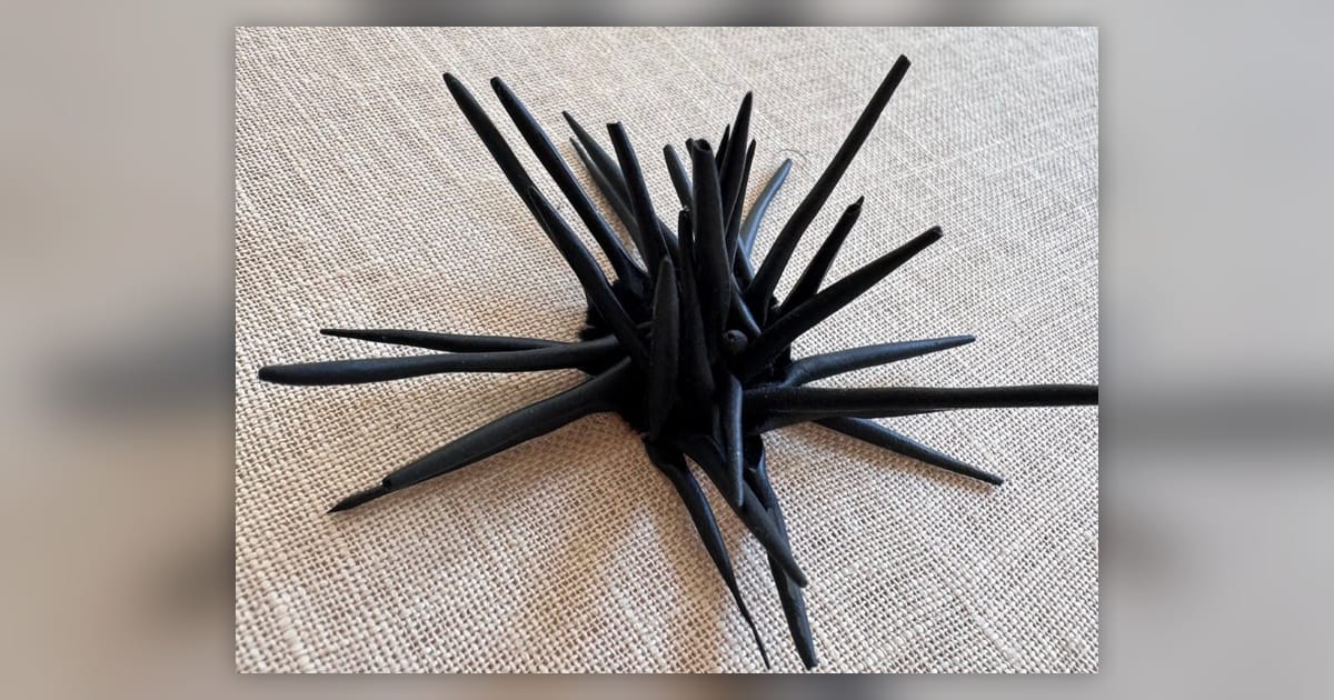 Handmade black polymer-clay spines prepared for a three-dimensional embroidered sea urchin.