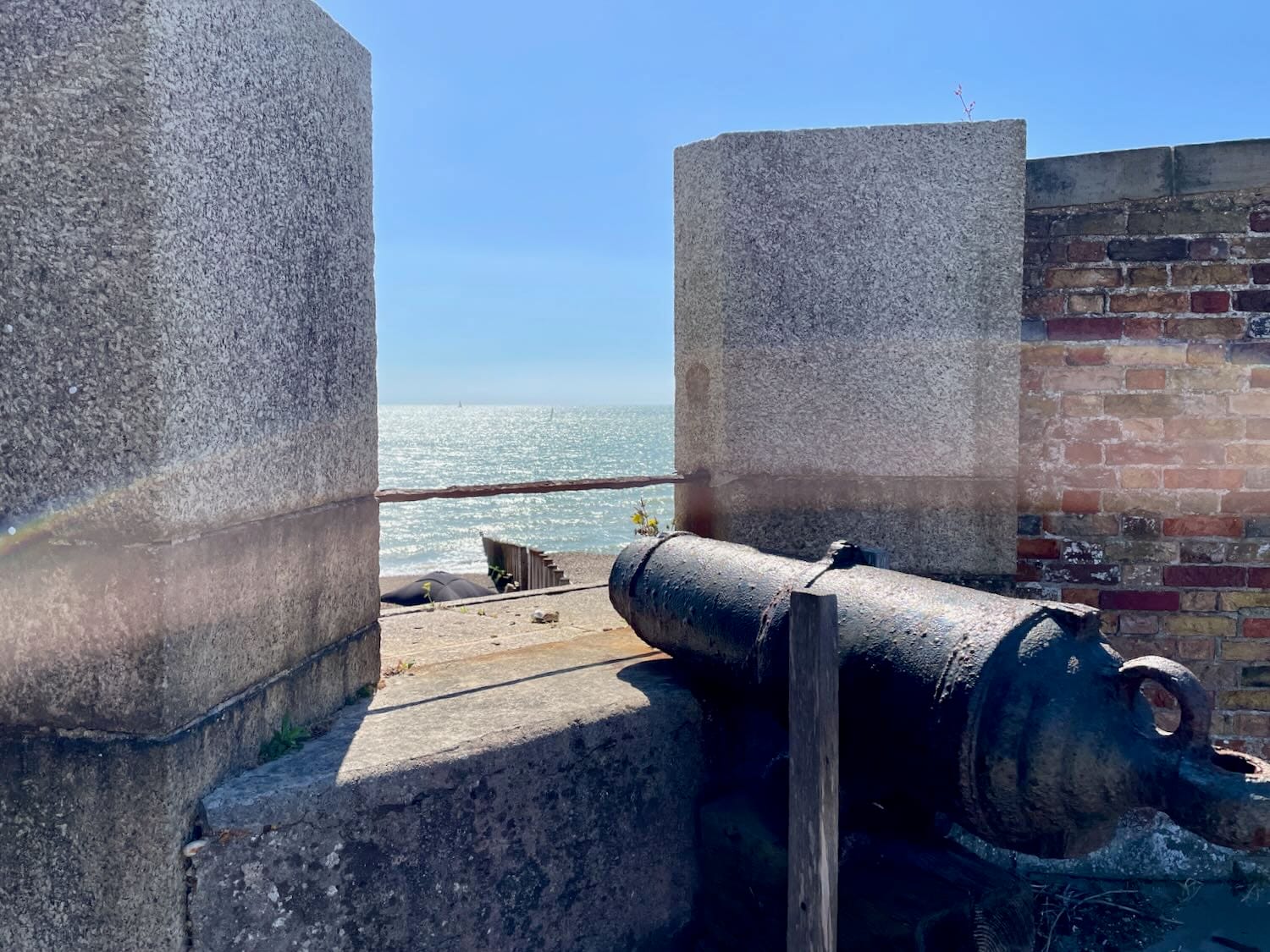 View out to sea through a gap in wall with a rusted cannon in the foreground