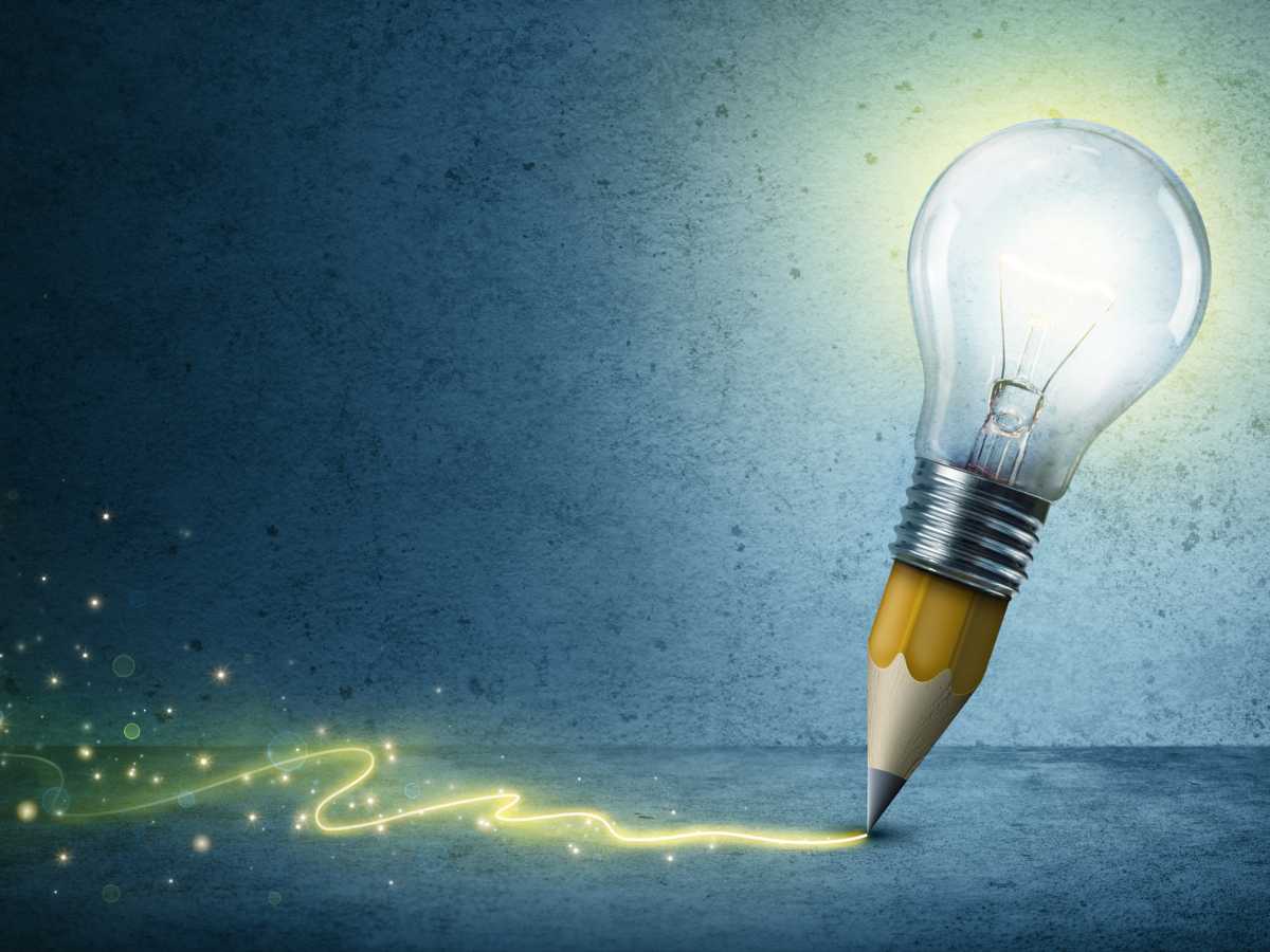 A pencil writing creatively with light from a light bulb.