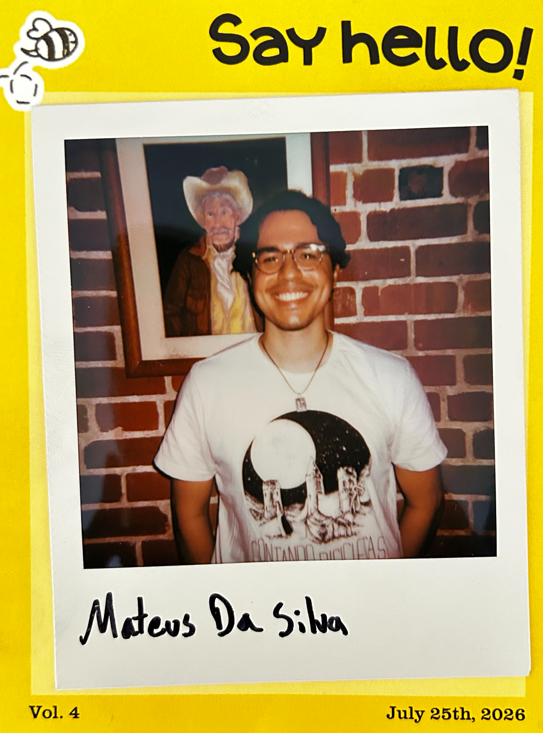 A polaroid of the author, framed in a yellow background with a drawing of a bee and "Say hello!" at the top, and "Vol. 4" and "July 25th, 2026" at the bottom. The author is smiling in front of a brick wall. A painting of a cowboy can be seen right behind him.
