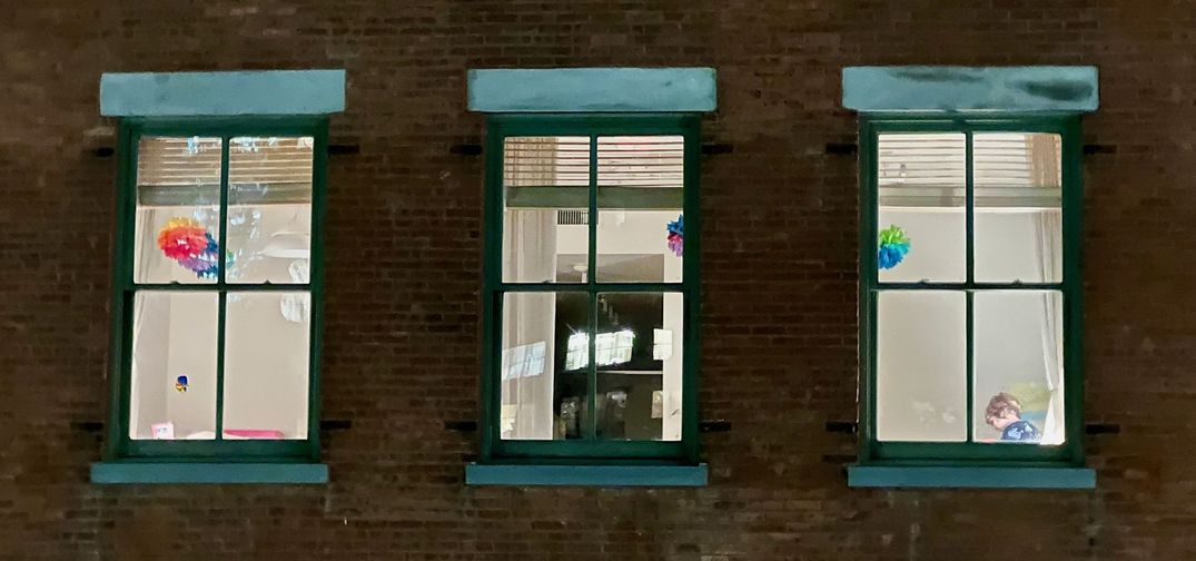 Kids reading as seen through apartment window from the outside.