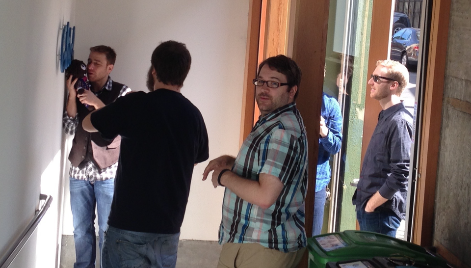 Stewart, Eric, Cal, and Johnny stand by the Glitch sign at the entrance of Slack's office