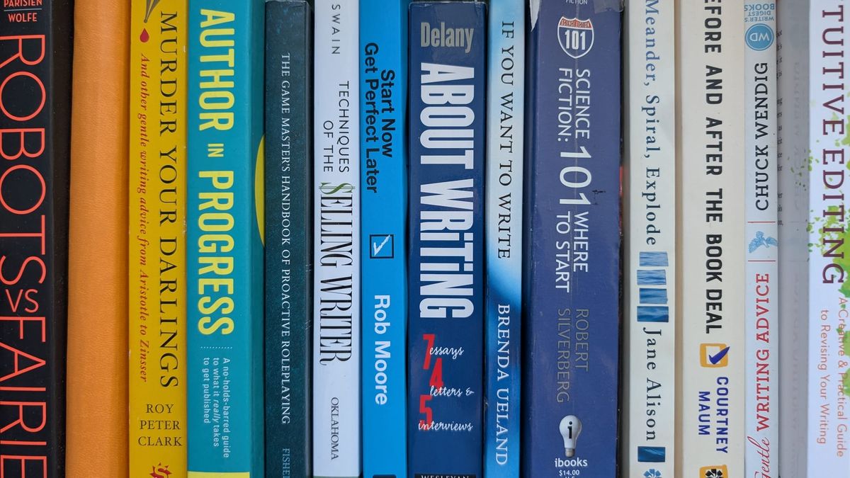 A bookshelf of mostly writing books, with the spines in a gradient from orange to blue to white.