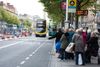 A crowd of passengers wait for a bus on O'Connell Street.