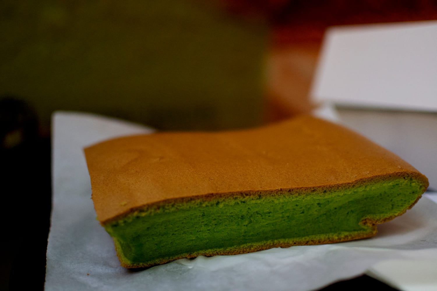 A square slice of cake with a green inside and brown crust.