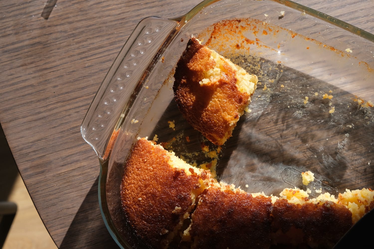 A transparency baking dish is half-filled with a spongey golden desert.