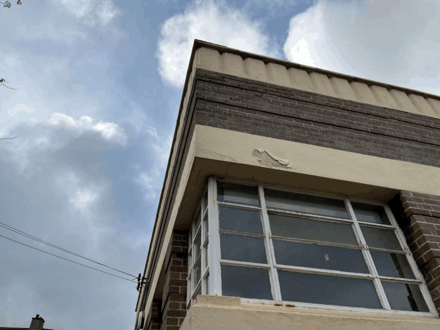 View of damaged brickwork, flaking paint and corroded window frame