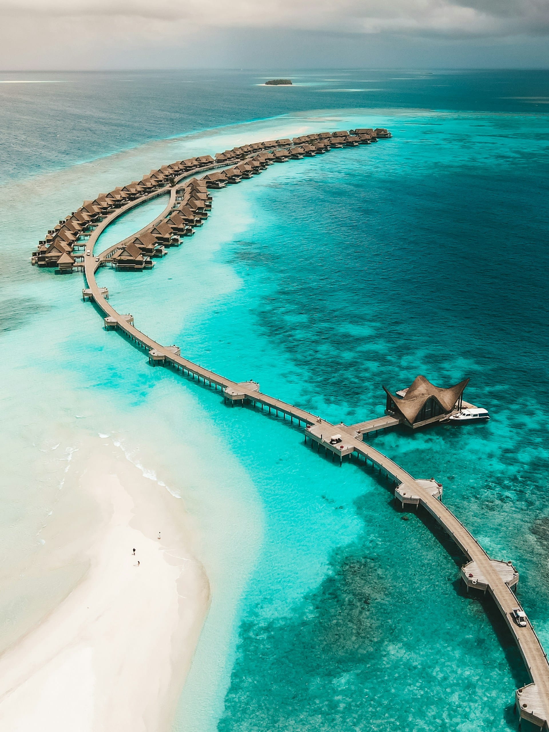Aerial view of a Maldivian atoll, turquoise water meeting white sand and coral reef