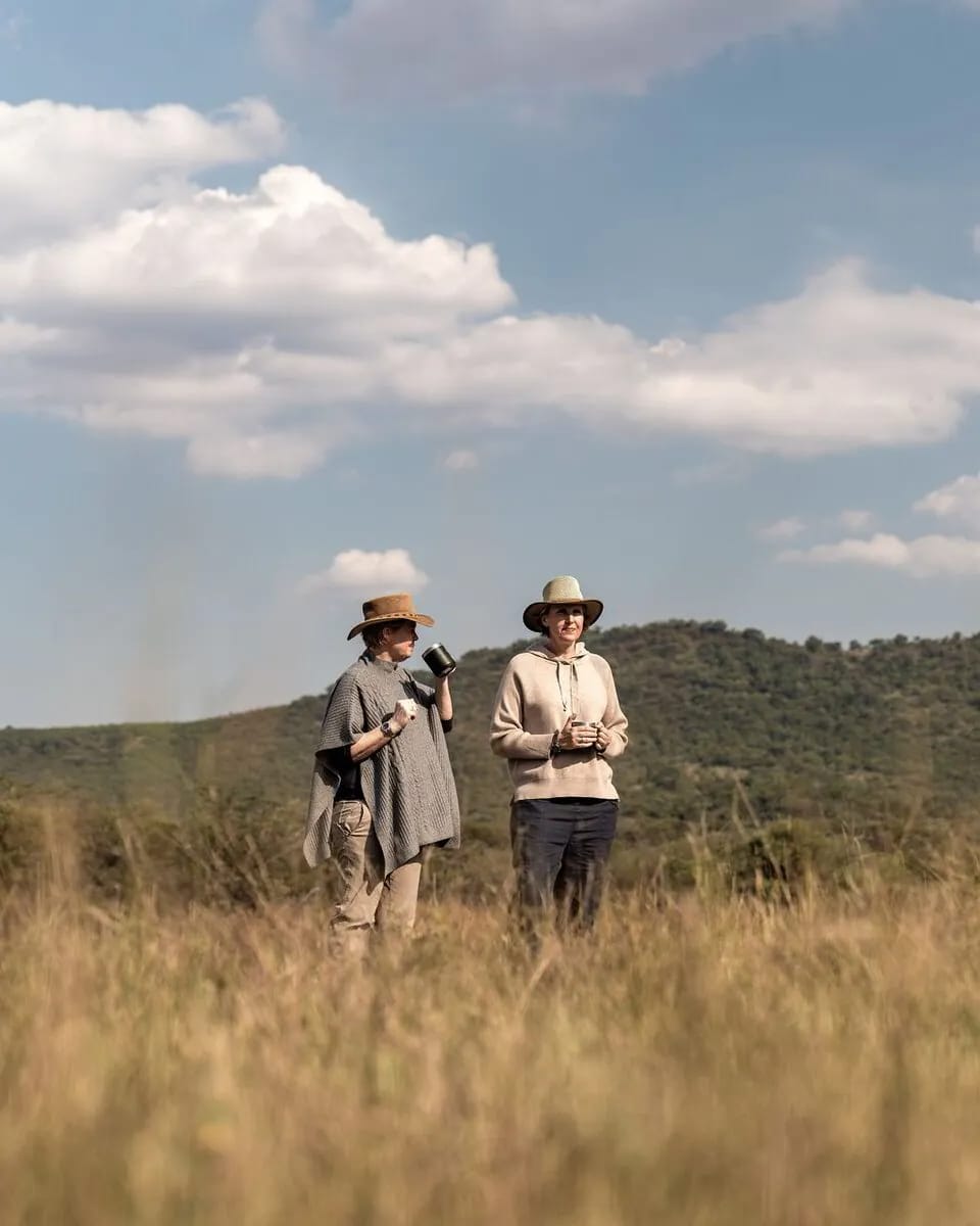 Vikki and Sian pausing for coffee in long winter grass on a walking safari