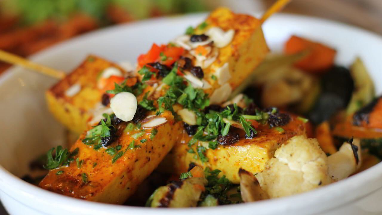 A bowl of roasted seasonal vegetables drizzled with herbed oil.