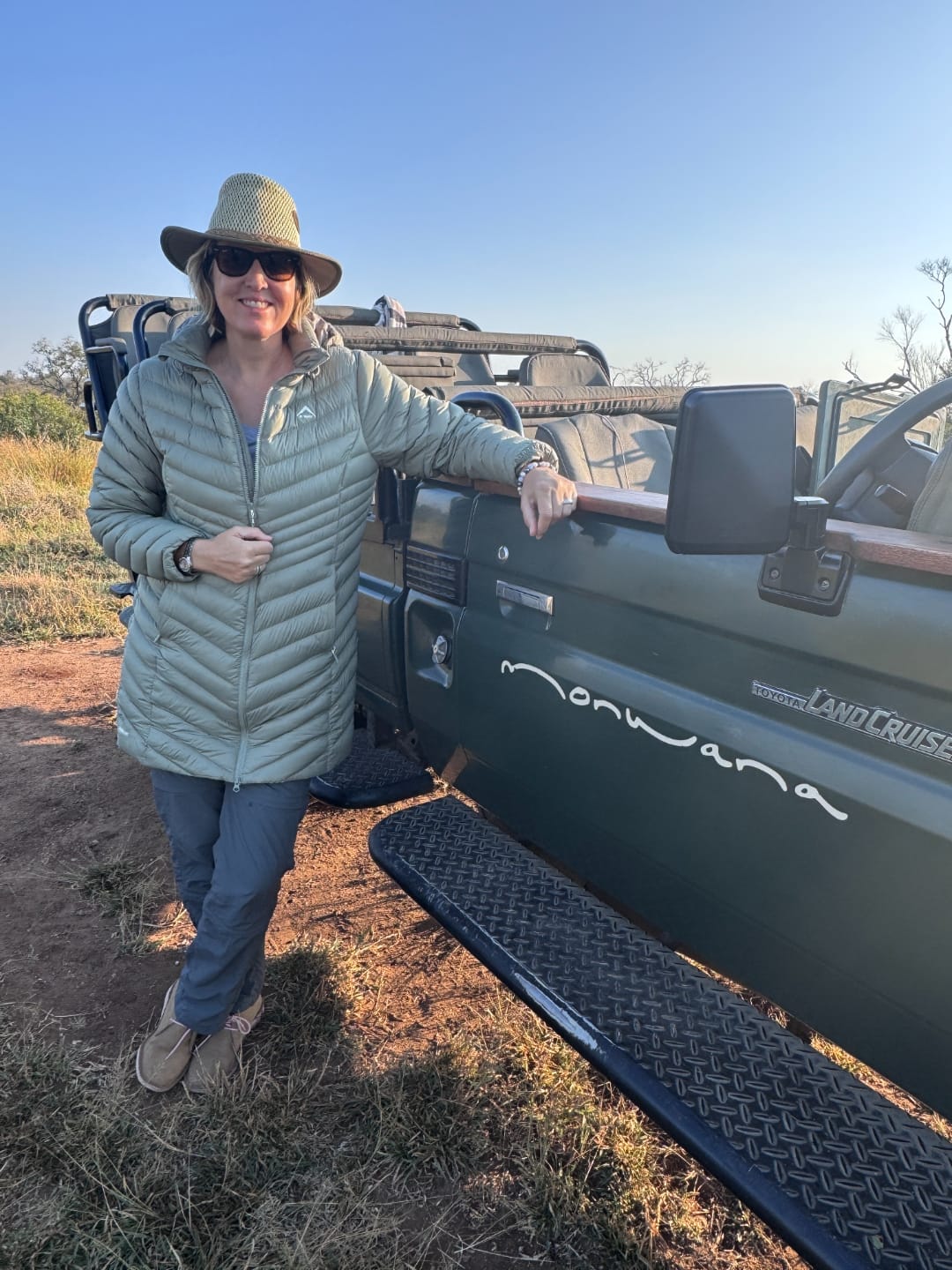 Vikki standing beside the open-sided Land Cruiser on the last morning, in the warm low light.