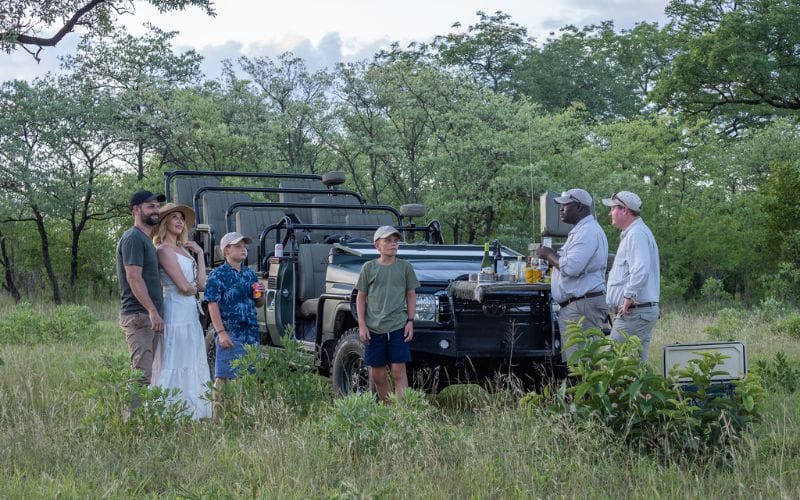 Children leaning over the side of an open game vehicle watching wildlife at a waterhole