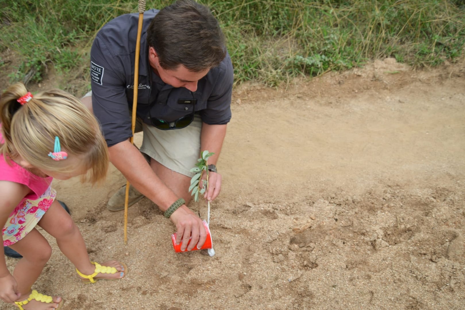 A guide showing a young guest how to take a plaster cast of an animal track in the sand