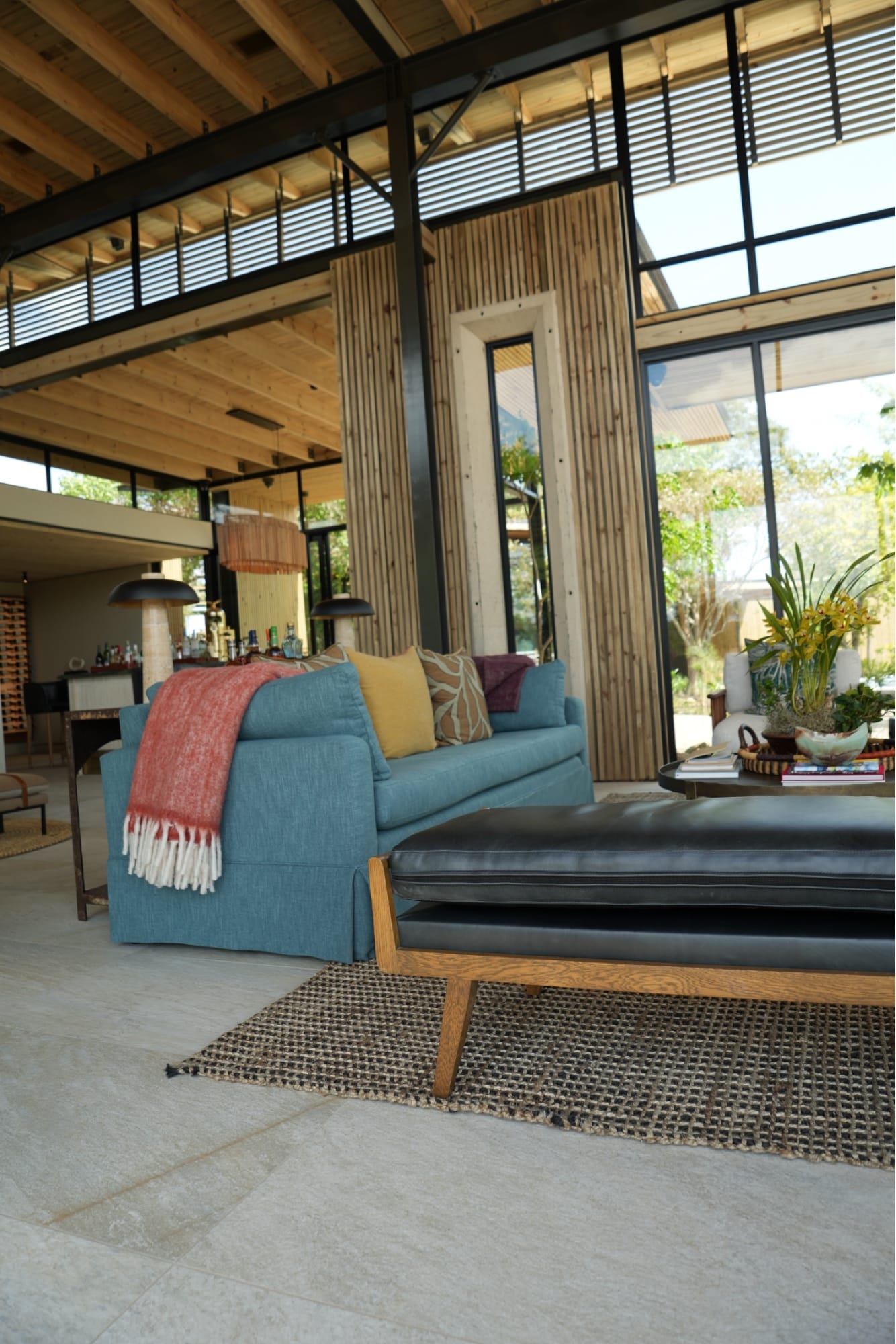 Indoor-outdoor lounge at Lion Sands Ivory Lodge with blue sofa, coral throw, and timber screens