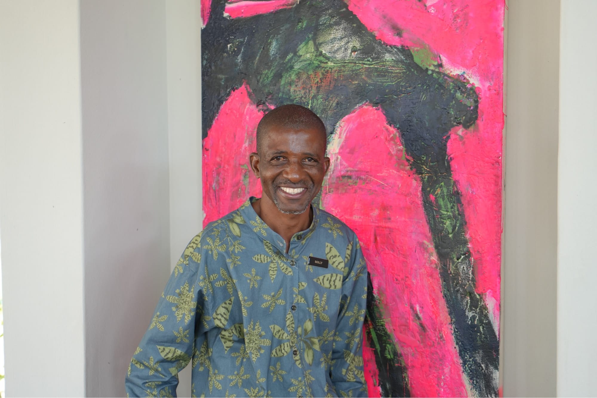 Solly, Lion Sands Ivory Lodge staff member, in the dining room in front of a pink and green abstract painting