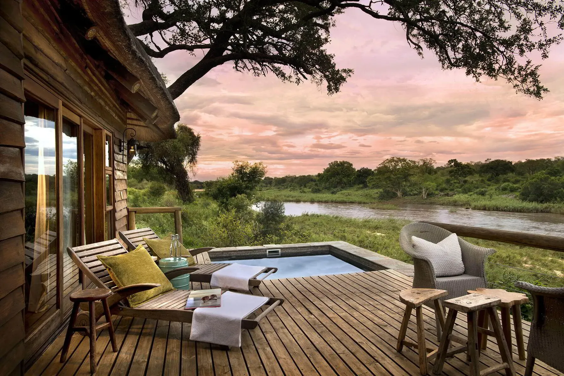 The private deck of Narina Suite at a Sabi Sand lodge, overlooking a waterhole surrounded by thick bushveld