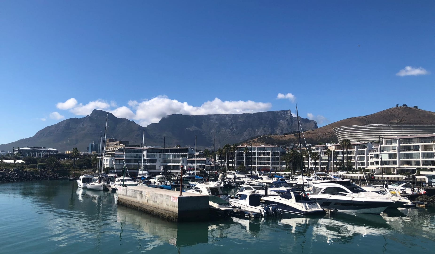 Table Mountain rising behind the V and A marina in Cape Town, yachts moored in still harbour water