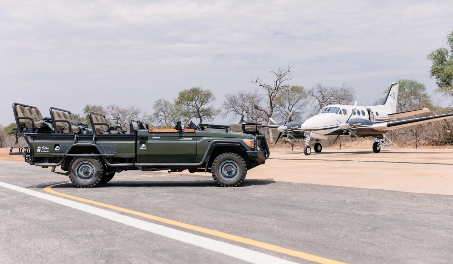 Open safari vehicle on the airstrip next to a small turboprop in the Sabi Sand, the bush-to-city transfer that makes a one-trip pairing possible