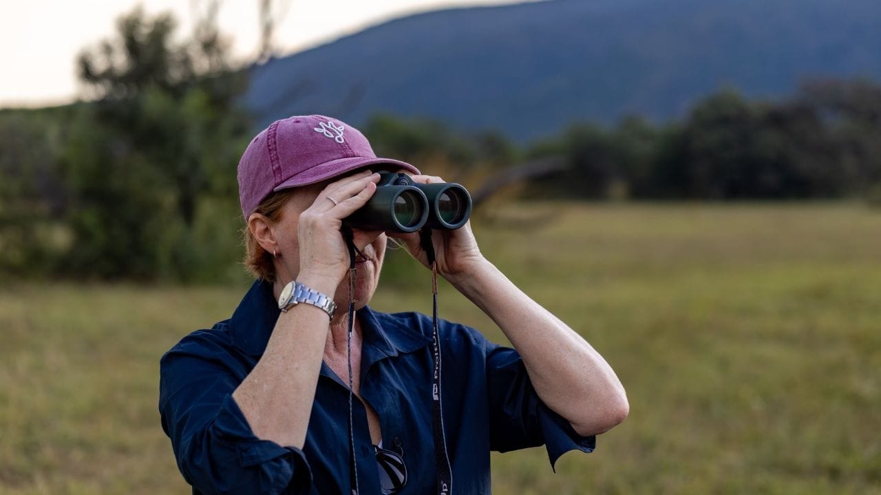 Vikki Jackson, co-founder of Marula Hill, scanning the bush with binoculars at golden hour