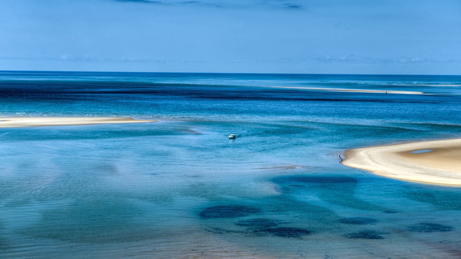 Empty beach at low tide in the Bazaruto Archipelago, dhow anchored offshore
